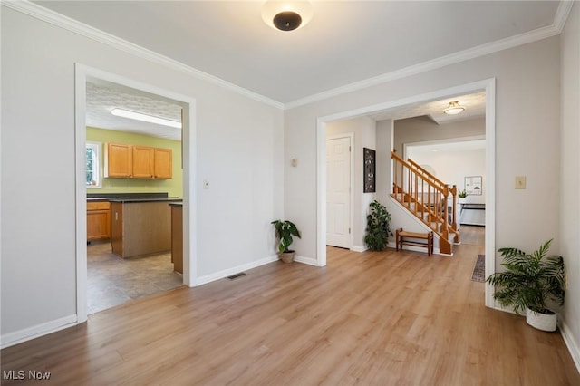 empty room with crown molding, stairway, baseboards, and light wood finished floors