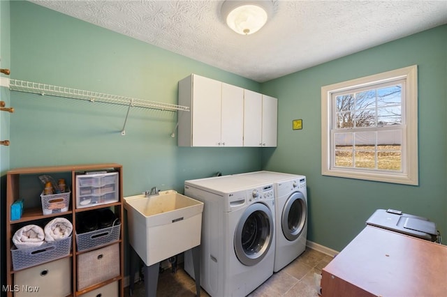 washroom with baseboards, washer and dryer, cabinet space, a textured ceiling, and a sink