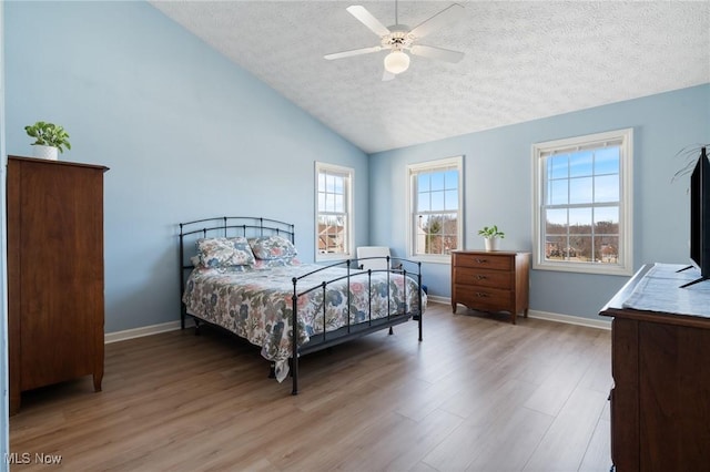 bedroom with wood finished floors, baseboards, ceiling fan, vaulted ceiling, and a textured ceiling