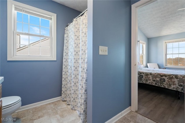 bathroom featuring baseboards, ensuite bath, vaulted ceiling, a textured ceiling, and toilet