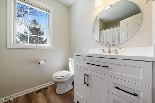 full bathroom with vanity, wood finished floors, visible vents, baseboards, and toilet