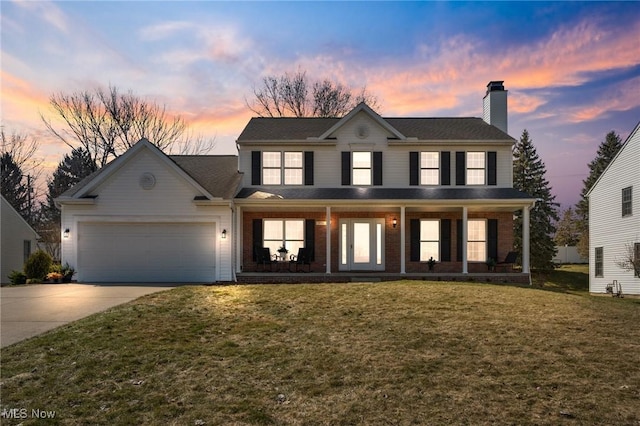 view of front of house with driveway, a porch, a chimney, a garage, and a lawn