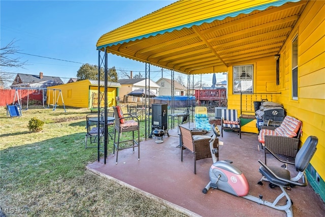 view of patio featuring an outbuilding, a playground, and fence