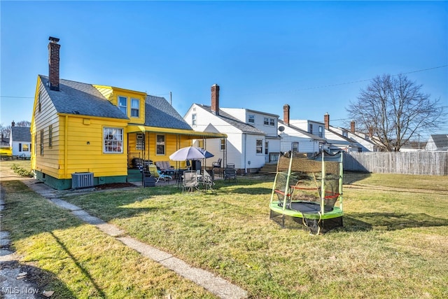 rear view of house with a patio area, a lawn, a chimney, and fence