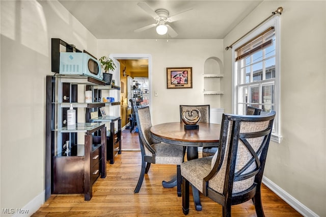 dining space featuring ceiling fan, baseboards, built in features, and wood finished floors