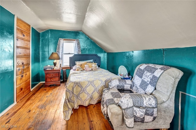 bedroom with wood-type flooring and vaulted ceiling