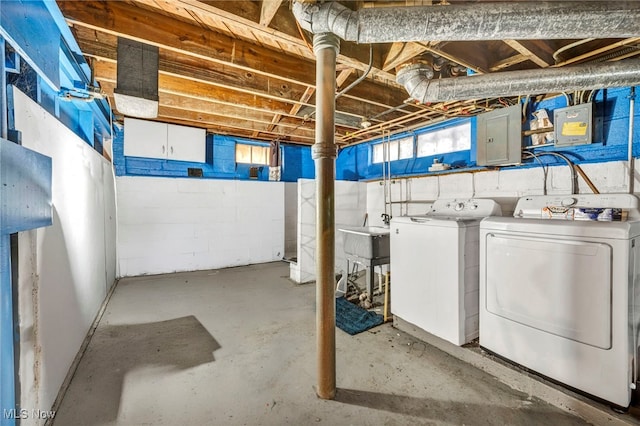 below grade area with a sink, concrete block wall, and washing machine and clothes dryer