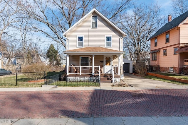 view of front of house featuring a porch, an outbuilding, a garage, and a fenced front yard