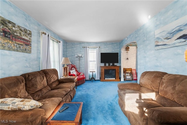 living room featuring a glass covered fireplace, wallpapered walls, and carpet floors