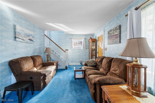 living room with wallpapered walls, stairway, carpet flooring, and a skylight