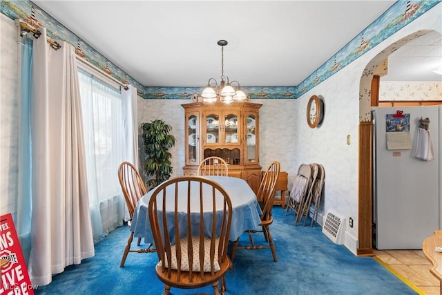 dining space featuring arched walkways, a chandelier, and wallpapered walls