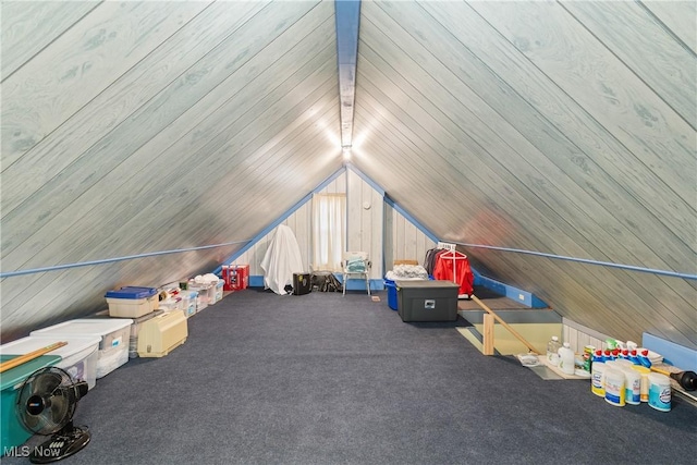 additional living space with lofted ceiling, wooden walls, and carpet