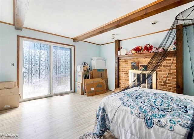 bedroom with beam ceiling, a brick fireplace, and access to exterior