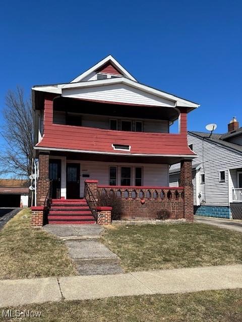 view of front facade featuring covered porch, a front yard, and a balcony