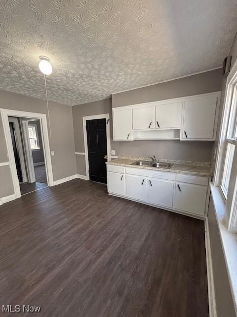kitchen featuring a textured ceiling, dark wood-type flooring, white cabinets, and a sink