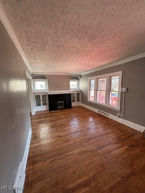 unfurnished living room featuring dark wood-style floors, baseboards, a fireplace, ornamental molding, and a textured ceiling