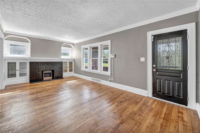 12117 Craven Ave, Cleveland, OH 44105 - unfurnished living room featuring a brick fireplace, hardwood / wood-style floors, a textured ceiling, crown molding, and baseboards