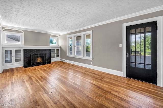 12117 Craven Ave, Cleveland, OH 44105 - unfurnished living room featuring ornamental molding, a brick fireplace, wood-type flooring, a textured ceiling, and baseboards