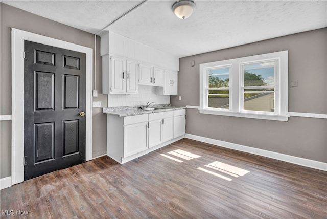 12117 Craven Ave, Cleveland, OH 44105 - kitchen with a sink, white cabinetry, dark wood-style flooring, baseboards, and backsplash