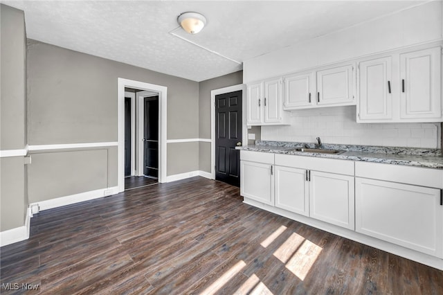 12117 Craven Ave, Cleveland, OH 44105 - kitchen featuring a sink, white cabinets, light stone countertops, baseboards, and dark wood finished floors