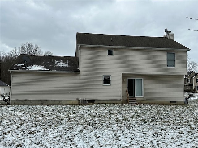 snow covered rear of property featuring a chimney