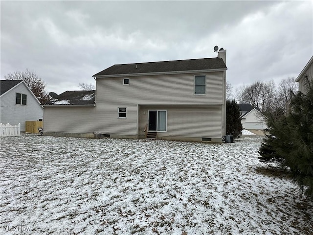 snow covered rear of property with fence and a chimney