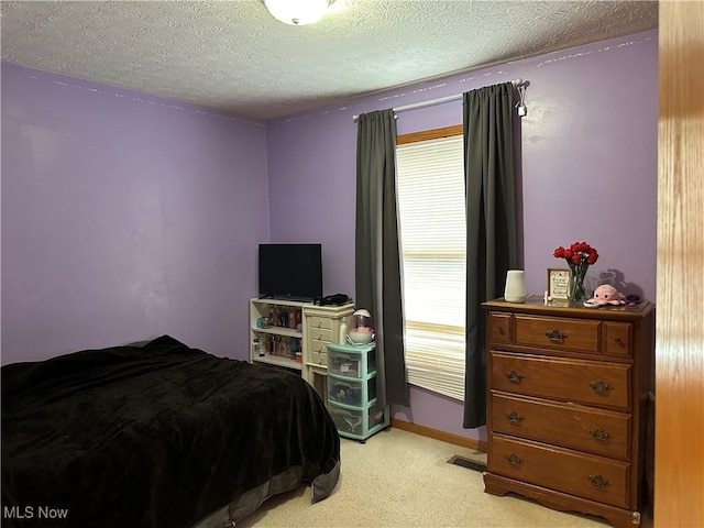 bedroom with multiple windows, light colored carpet, and a textured ceiling