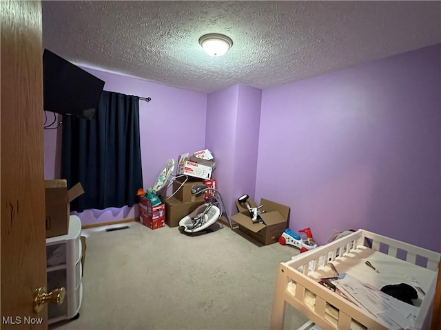 recreation room with carpet, visible vents, and a textured ceiling