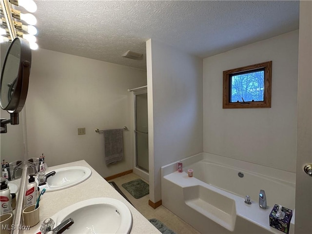 full bath with a textured ceiling, a garden tub, a stall shower, and a sink