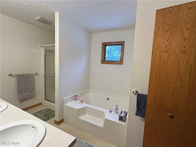 bathroom featuring a sink, a textured ceiling, a stall shower, and a bath