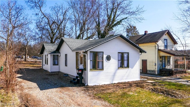 exterior space featuring dirt driveway and roof with shingles