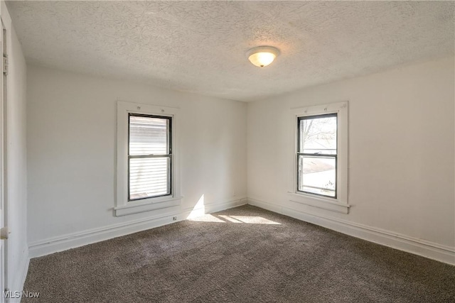 carpeted spare room featuring baseboards and a textured ceiling