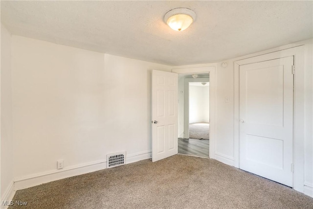 empty room featuring baseboards, carpet, visible vents, and a textured ceiling