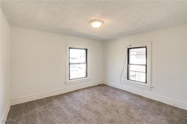 carpeted spare room featuring baseboards and a textured ceiling