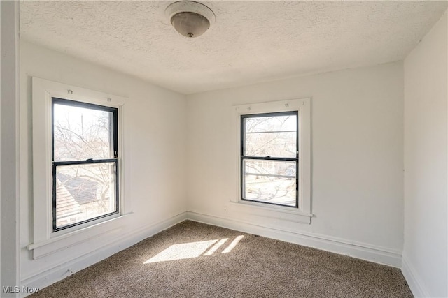 spare room featuring a textured ceiling, baseboards, and carpet floors