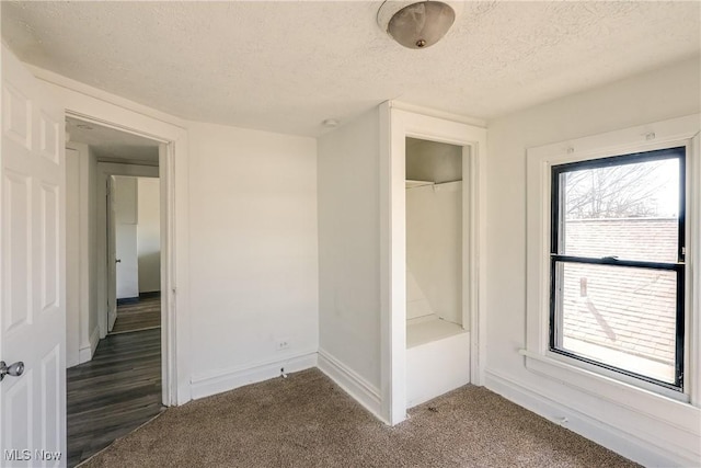 unfurnished bedroom featuring a closet, baseboards, a textured ceiling, and carpet