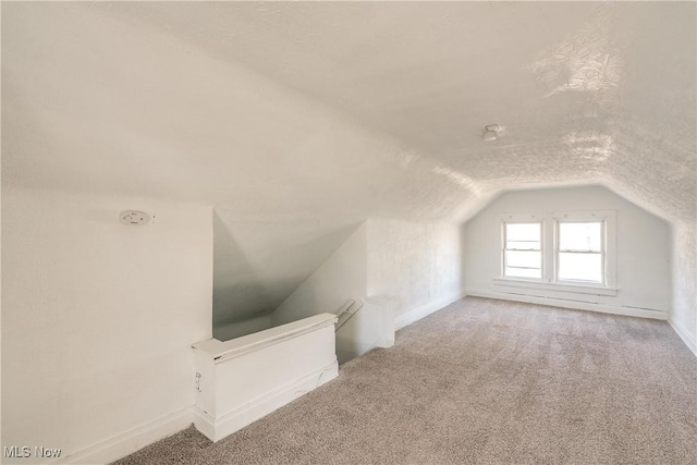 bonus room featuring lofted ceiling, carpet, baseboards, and a textured ceiling