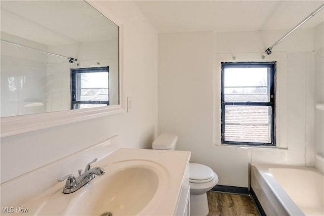 bathroom featuring toilet, wood finished floors, a bathtub, walk in shower, and vanity