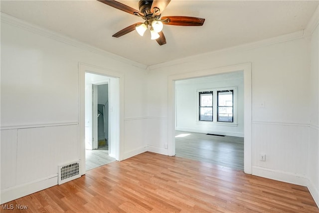 empty room with visible vents, crown molding, and light wood-type flooring