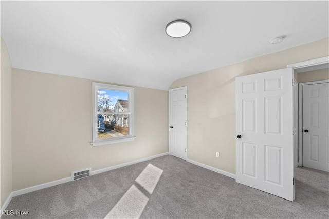 unfurnished bedroom with visible vents, baseboards, carpet, and vaulted ceiling