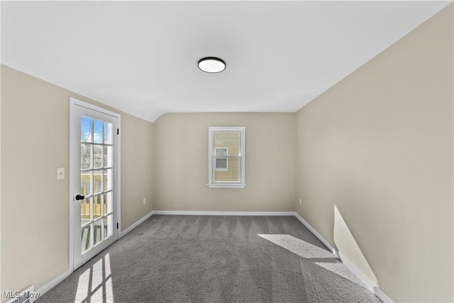 empty room featuring lofted ceiling, carpet flooring, and baseboards