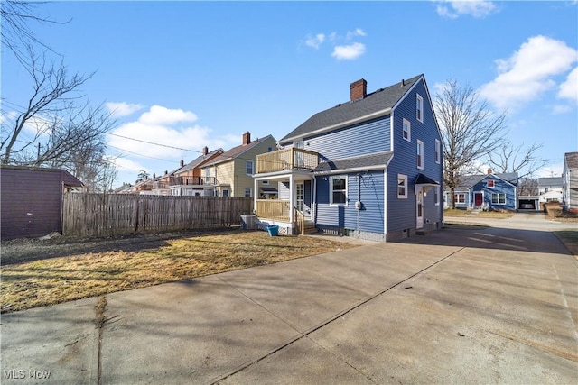 view of front of home featuring a shingled roof, a chimney, and fence