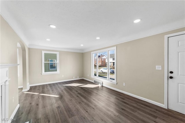 unfurnished living room with wood finished floors, baseboards, recessed lighting, arched walkways, and ornamental molding