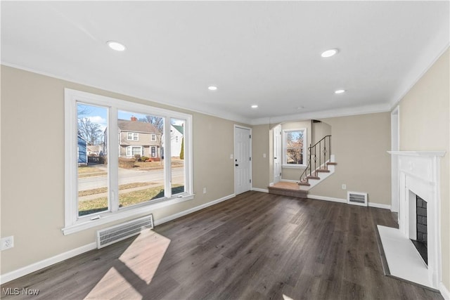 unfurnished living room with stairs, dark wood finished floors, a fireplace, and visible vents