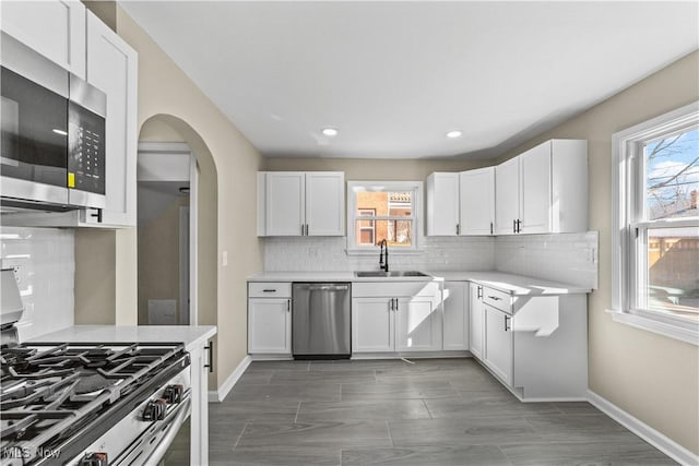 kitchen featuring plenty of natural light, arched walkways, appliances with stainless steel finishes, and a sink