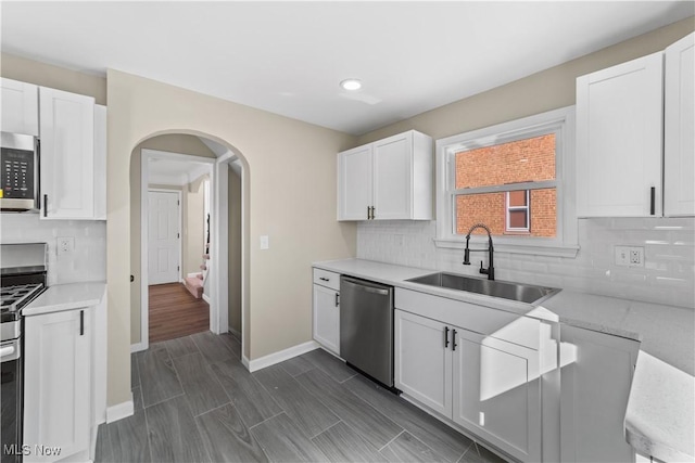 kitchen with a sink, stainless steel appliances, arched walkways, and light countertops