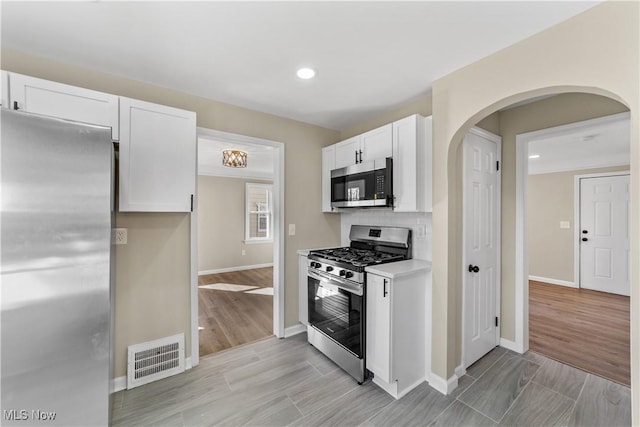 kitchen with light wood-type flooring, visible vents, appliances with stainless steel finishes, white cabinets, and light countertops