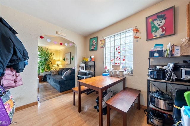 office with wood finished floors, arched walkways, and baseboards