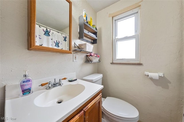 bathroom featuring a shower with shower curtain, toilet, vanity, and a textured wall