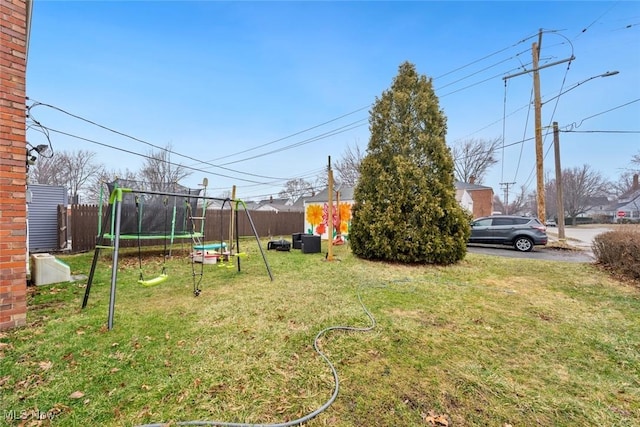 view of yard with a trampoline and fence